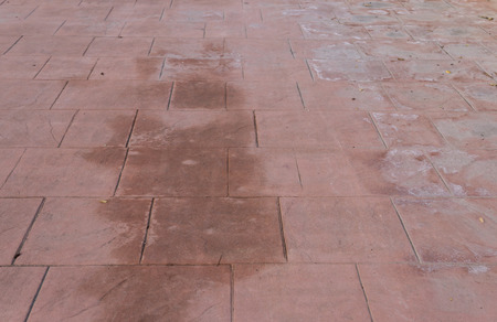 Stamped concrete floor outdoor pavement worn out, appearance of natural stone, mimics colors and textures of material pavers, red square pattern wet and humidの写真素材