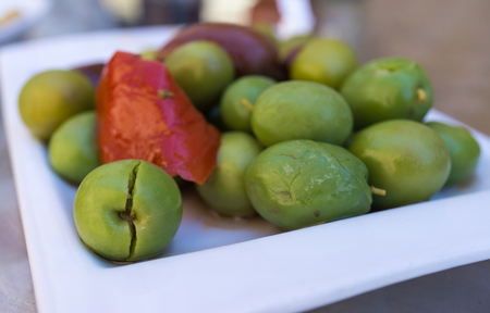 Spiced olives in a small plate on the tapas bar table a typical Spanish black and green split olive. With the red touch of a pepperの写真素材