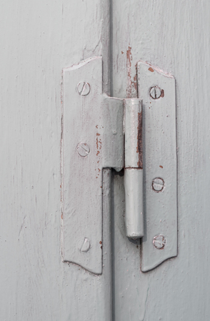 Old door hinge on vintage window, painted covering wood, metal and screwsの写真素材