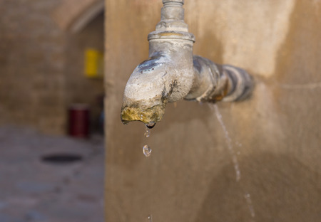 close-up old faucet with lime deposit calcified water flowingの写真素材