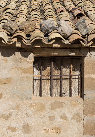 Old tiled roof of a rustic cottage, fastened with stones aboveの写真素材