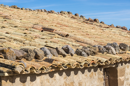 Old housing roof tiled of a rustic cottage, fastened with stones aboveの写真素材