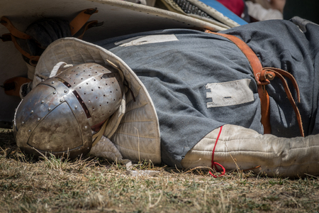 Medieval knight fallen in battle, on a reenactment with costumed characters and medieval armor with chainmail, helmet swords and shields. Medieval demonstration and recreationの写真素材