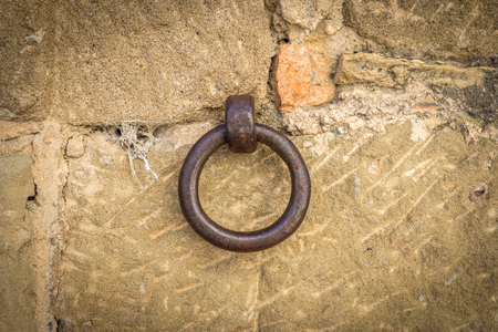 old iron ring a little rusty embedded in a stone wall, used to leave tethered animals like horses or mulesの写真素材