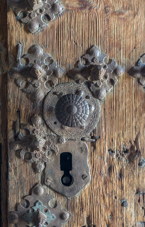old iron lock, on a wooden door, with ornamental details in the shape of a flowerの写真素材