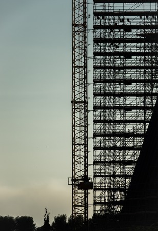 silhouette of scaffolding, working at building construction, profile sunset light structure of scaffolding and cranesの写真素材