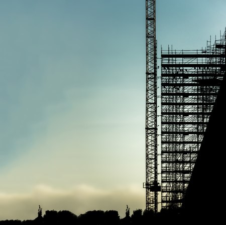 silhouette scaffolding building construction crane with copy space for text, black profile structure of scaffolding sunset at city, architecture engineering diagonal building structureの写真素材
