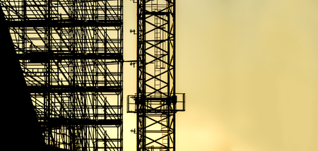 silhouette scaffolding with copy space for text, building construction, black profile structure of scaffolding warm orange colors sunset, construction, architecture engineeringの写真素材
