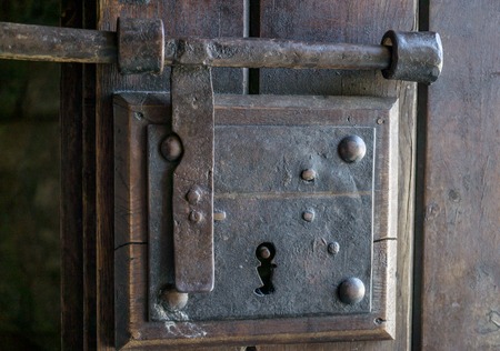 old iron door lock, on a wooden door, with ornamental detailsの写真素材