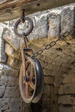Old pulleys with chains a little rusty, fastened to a wooden beamの写真素材