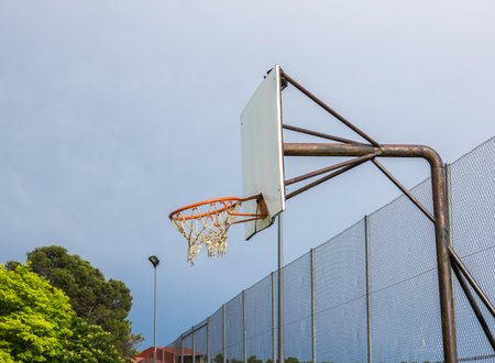 broken basketball hoop of a neighborhood court, on blue sky backgroundの写真素材