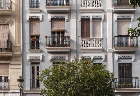 several windows of old apartment residential building with an orange tree on the street. Colorful facade at Valencia neighborhood, vintage apartment architectureの写真素材