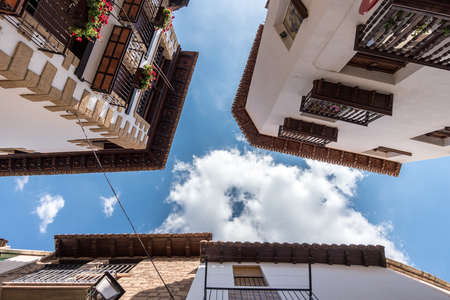 Wooden eaves of houses nearby in an old village of Spain, carved wood carving low angle shooting blue sky and clouds views, traditional architecture buildingの写真素材