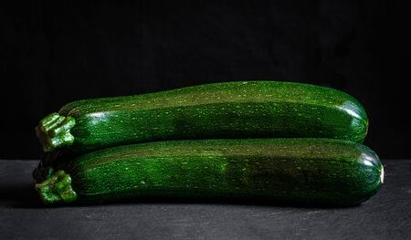 two zucchini on black background green food fresh vegetableの写真素材