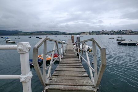 dock to access many Small wooden fishing boat drifting Castropol Asturias Spain cloudy day ria de Ribadeo port town on the shore of Cantabrian Seaの写真素材