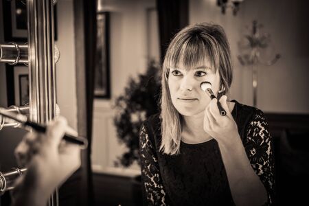 woman looking into a vintage mirror at herself and use cosmetic vanity make up accessories, makeup dressing tableの写真素材
