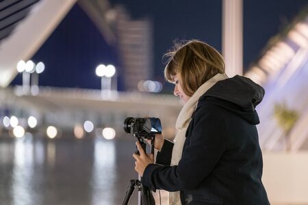 young woman traveler landscape photography with mirrorless camera travel night photo with tripod to avoid shakeの写真素材