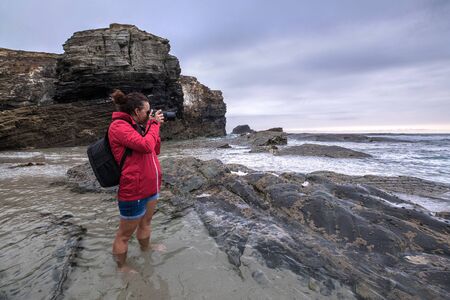 adventure explore woman walking on the beach traveler landscape photography with bridge camera on the sea cliff beach travel photoの写真素材