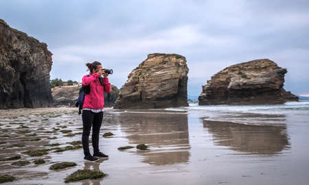 adventure explore woman walking on the beach traveler landscape photography with bridge camera on the sea cliff beach travel photoの写真素材