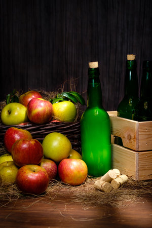 Asturian cider bottles many red and green apples at basket over wooden backgroundの写真素材