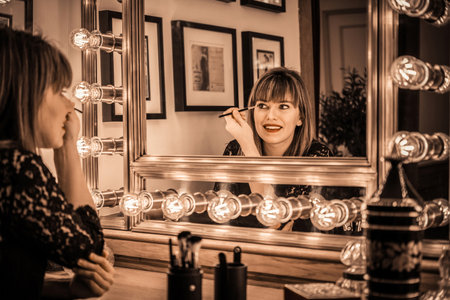 Woman eye makeup in a vintage bathroom headdress, beauty, elegance and glamor, mirror with decorative lightsの写真素材