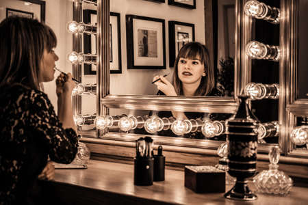 Woman eye makeup in a vintage bathroom headdress, beauty, elegance and glamor, mirror with decorative lightsの写真素材