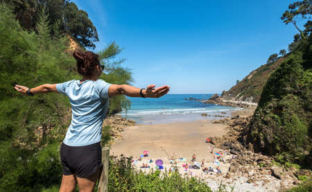 girl with outstretched arms at the end of the beach viewpoints path, Senda de los Miradores Aguilar Asturias Muros del Nalon Spain, adventure tourismの写真素材