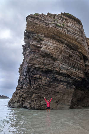 adventure woman explorer girl impressed by size and height cliff in the sea Playa de las Catedrales Galicia Spain, cathedral beach travelの写真素材