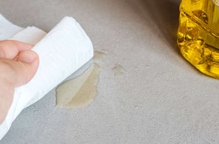 hand wiping spilled oil stain on cement floor with absorbent paper on concrete floor, washable microcement surfaceの写真素材