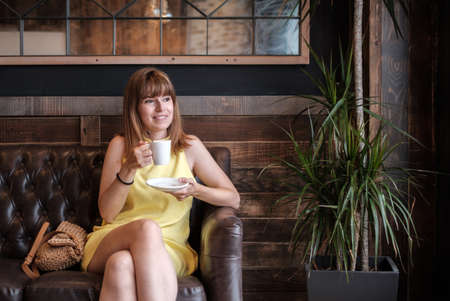 woman drinking coffee on the sofa a stylish interior of coffee shopの写真素材