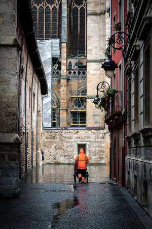 municipal worker with with waterproof uniform collecting garbage with his cart, city Leon spain rainy dayの写真素材