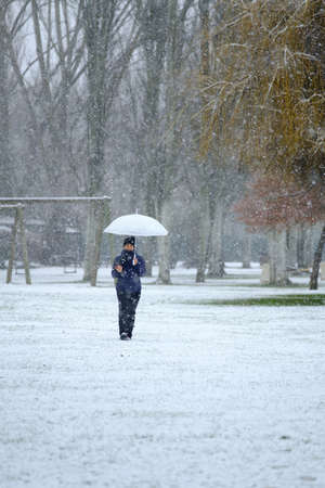 Candamia park snowy day in winter girl walking with her photo camera and holding an umbrella, Leon Spainの写真素材
