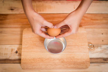 Woman prepeared eggs for cooking on wooden tableの写真素材