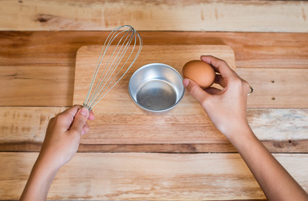 Woman prepeared eggs for cooking on wooden tableの写真素材