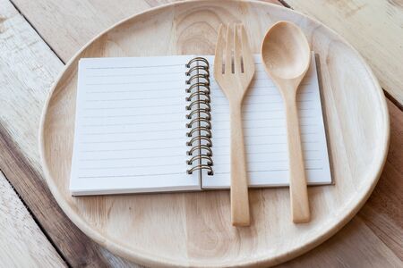wood dish,wood fork and notebook on wooden table.with Text Spaceの写真素材