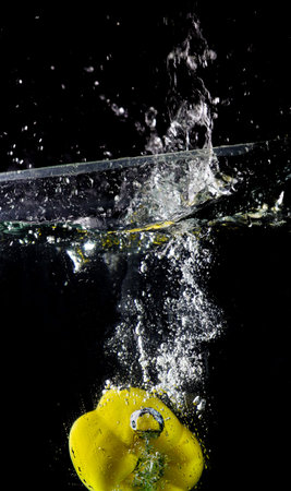 Bubbles caused by a Yellow bell pepper were thrown into the water. On the black background.