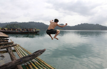 Motion blur shot of a young man jumping into water at thailandの写真素材