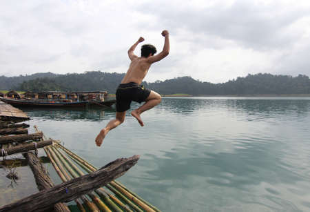Motion blur shot of a young man jumping into water at thailandの写真素材