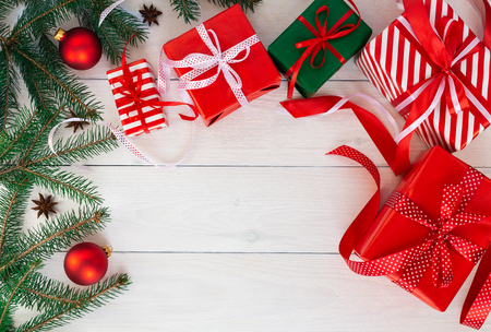 Christmas festive background, gifts with ribbons and bows, branches of green spruce with Christmas decorations on a white wooden backgroundの写真素材