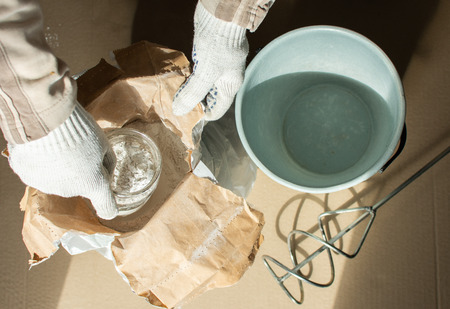 Man builder prepares a mixture for putty, bag with gypsum putty and drill mixerの写真素材
