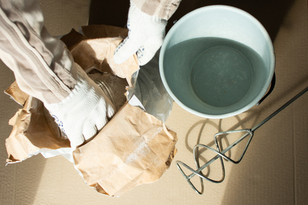 Man builder prepares a mixture for putty, bag with gypsum putty and drill mixerの写真素材