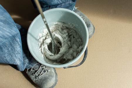 Man builder mixes gypsum putty in a bucketの写真素材