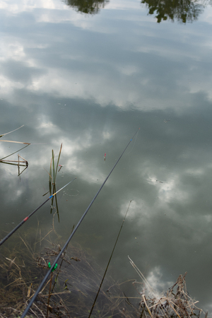 Reflection of clouds in the lake, fishing rod float in water, fishingの写真素材