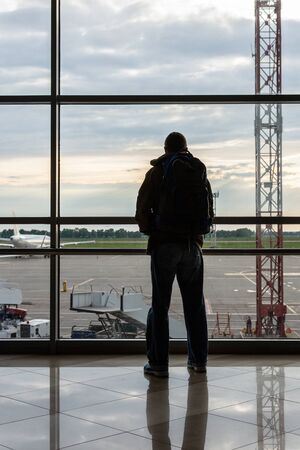 Silhouette of man with luggage on the background of a window at the airport, air transportationの写真素材