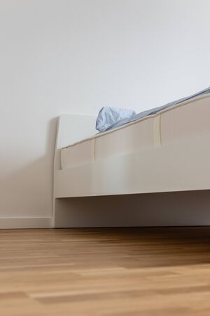 Part of the home or hotel interior, white bed with mattress and blue linensの写真素材