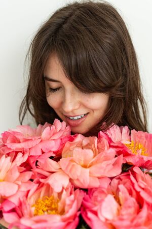 Beautiful girl is happy with flowers on her birthday, face of a girl close up with peonies, valentine's dayの写真素材