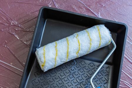 Paint tray and roller on the floor covered with oilclothの写真素材