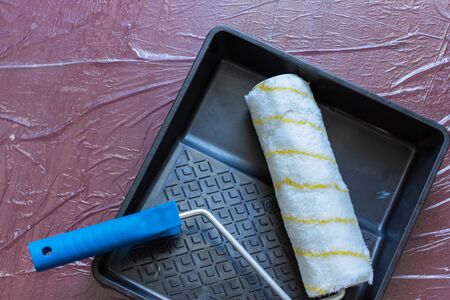 Paint tray and roller on the floor covered with oilclothの写真素材