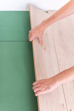 Installation laminate or parquet in the room, worker installing wooden laminate flooring, environmentally friendly soundproofing sheetsの写真素材