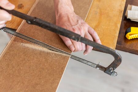 Installation laminate or parquet in the room, worker cuts a laminate of a certain length with a sawの写真素材